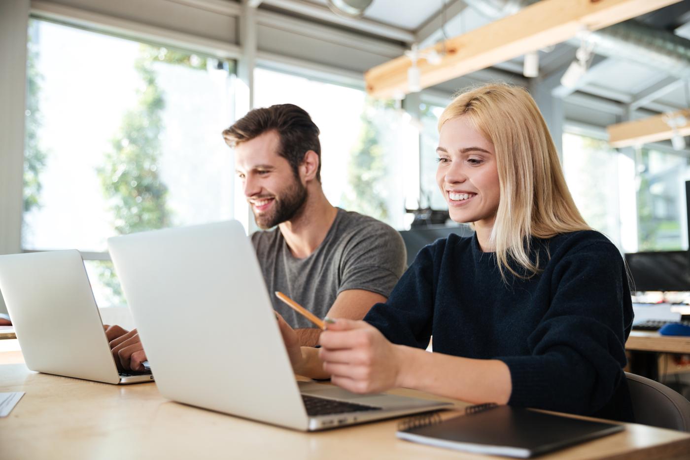 Un homme et une femme souriants devant leur ordinateur